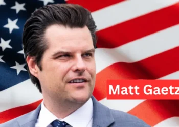 "Matt Gaetz speaking at a political event, wearing a suit and tie, representing Florida as a congressman."